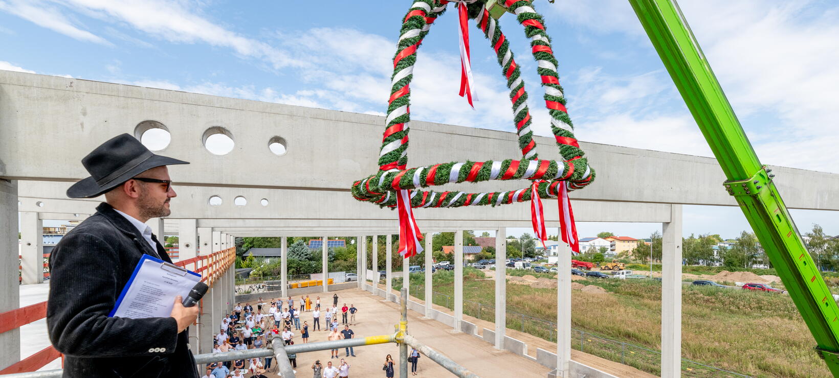 Polier Maurice Kugel beim Richtspruch mit Blick auf den Richtkranz und die Gäste